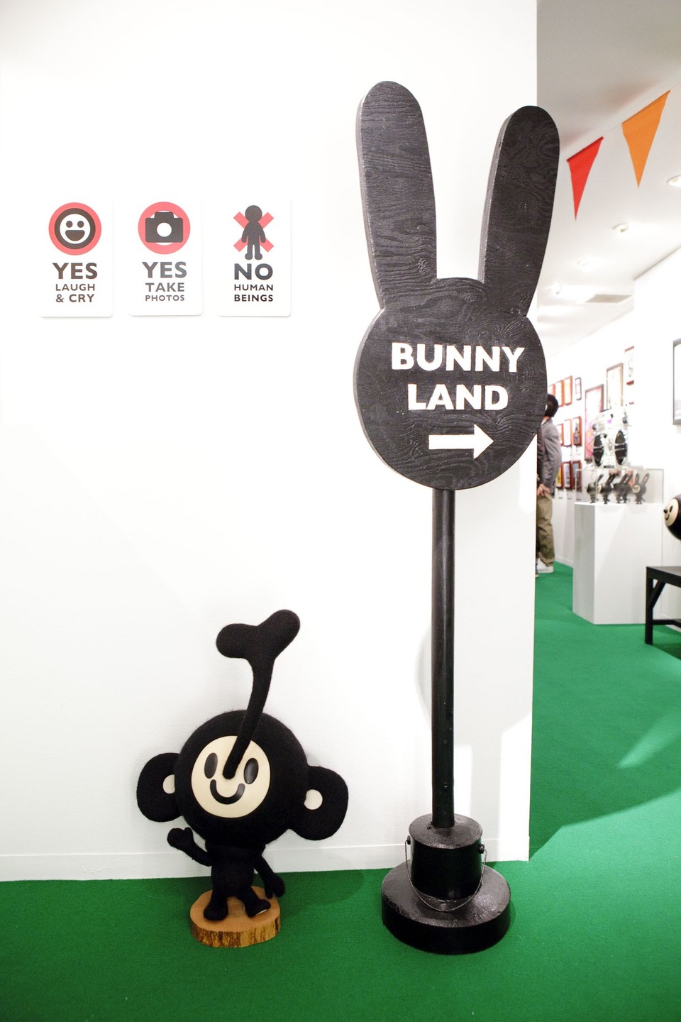 BUNNY LANDと書かれたウサギ形の矢印看板。足元に小さなウサギの立体作品があり、壁にはYES、YES、NOのルールのサインが並ぶ。